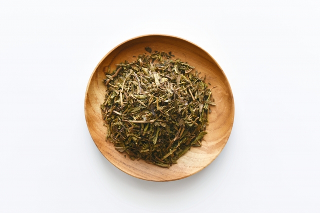 Feuilles et tiges de hojicha dans une coupelle en bois