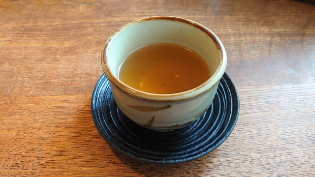 Tasse de hojicha infusé posée sur une soucoupe noire