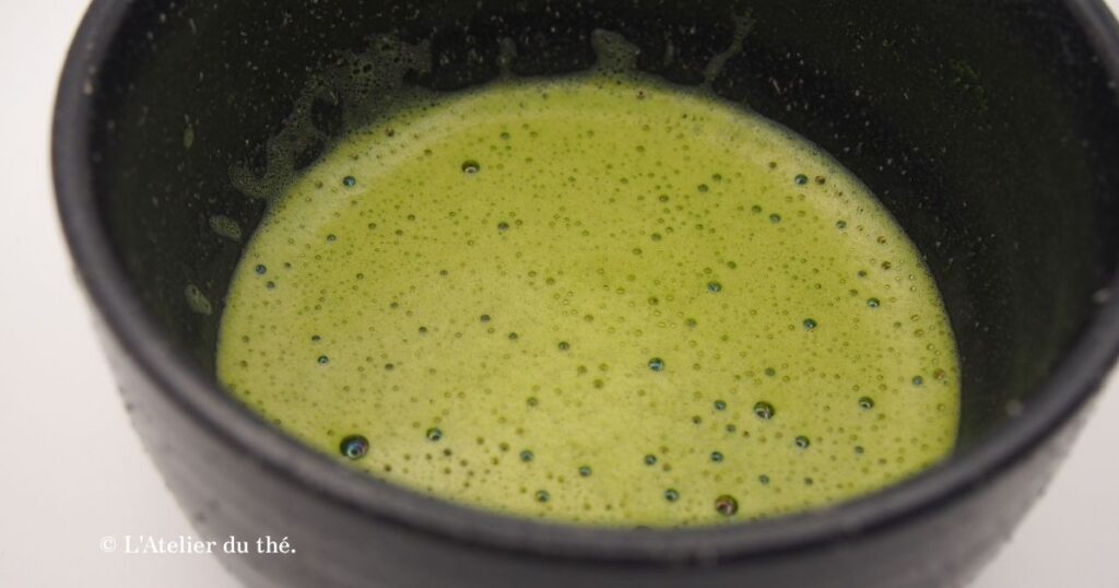 Gros plan sur la mousse fine et vert-jaune d’un matcha préparé avec une eau douce