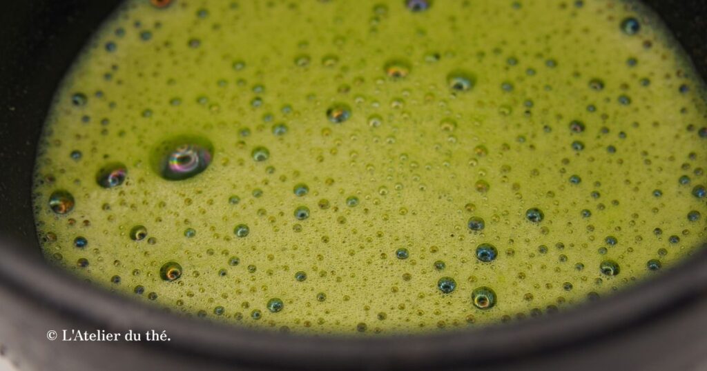Gros plan sur la mousse aux grosses bulles et un peu terne d’un matcha préparé avec l’eau du robinet